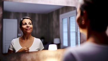 Une femme se regardant dans le miroir avec un air confiant et satisfait.