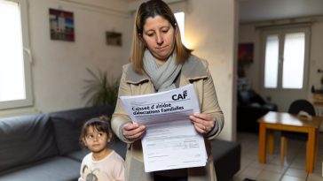 Une femme tenant dans ses mains des documents de la CAF avec un enfant à ses côtés.