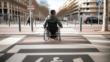 Une personne en fauteuil roulant traversant un passage piéton.