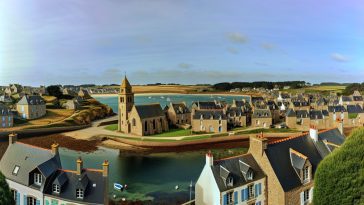 Une vue panoramique d'un charmant village breton avec ses maisons traditionnelles et son église, situé au bord de la mer près de Saint-Malo.