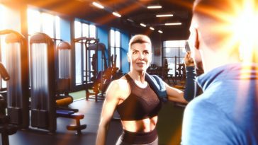 Une femme qui se regarde dans le miroir, admirant les résultats visibles de son entraînement physique régulier.