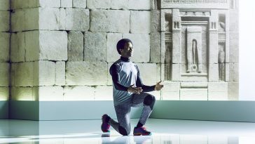 Une femme en tenue de sport effectuant un exercice de pilates contre un mur.