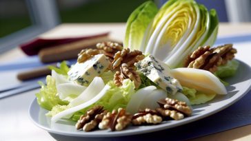 Une salade fraîchement préparée avec des endives, des noix et du roquefort disposés de manière appétissante sur une assiette.